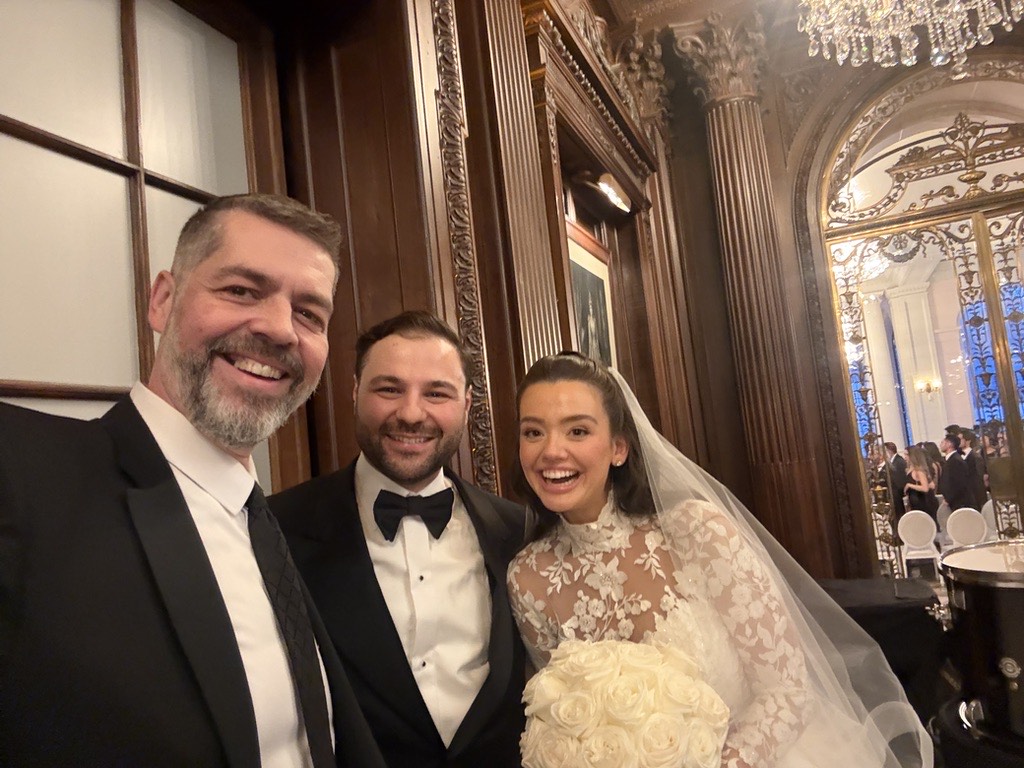 Phil with a couple in an ornate ballroom