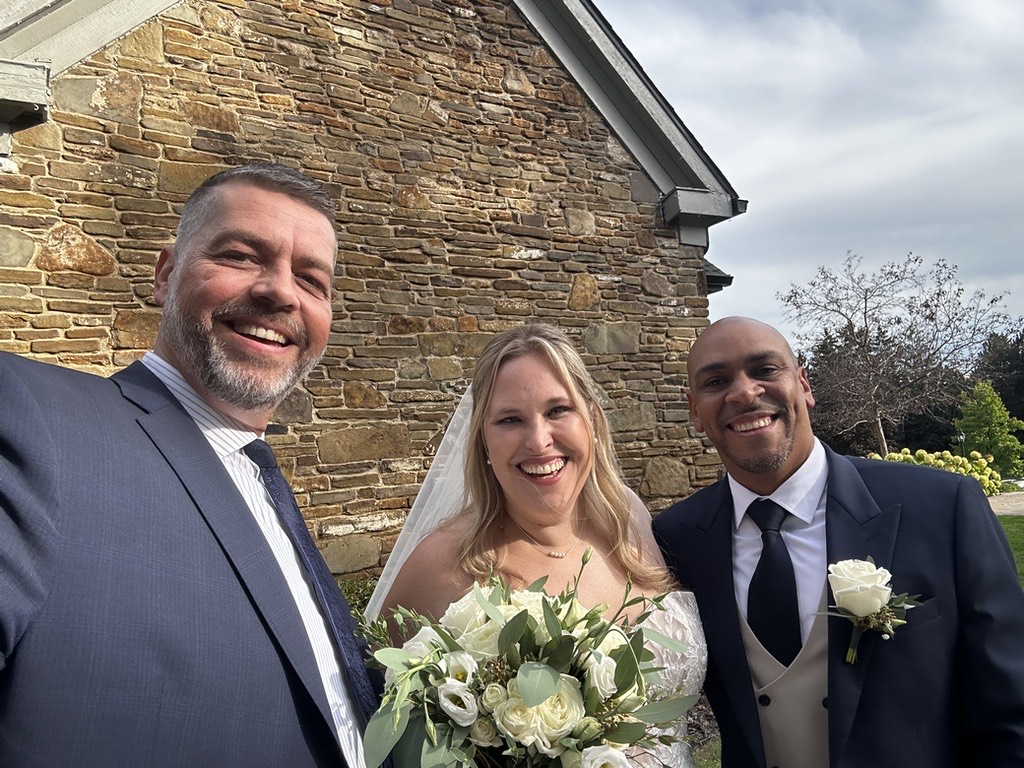 Phil with a smiling couple outside a stone chapel