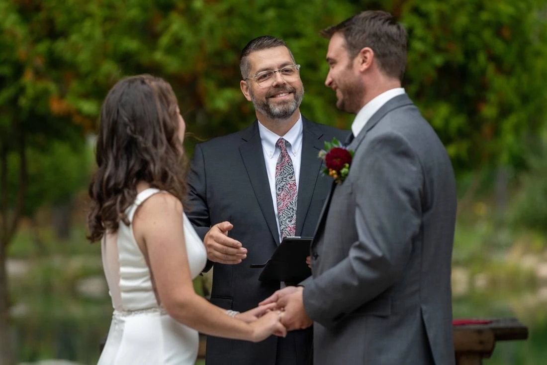 Phil Smith smiling as he leads a couple through their vows